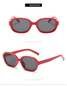 Close-up of red oval sunglasses with silver metal studs and dark lenses for women