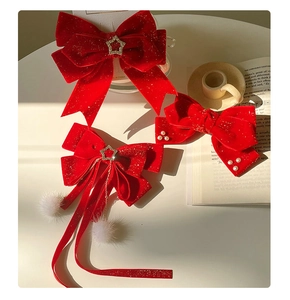Detailed view of red velvet bow hair clips with pearls, star pendants, and white fur balls