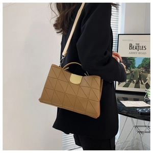 Detail of khaki shoulder bag featuring geometric triangle quilting and cream flap accent