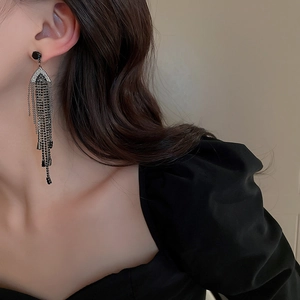 Close-up of elegant black tassel earrings with rhinestones on model for formal wear