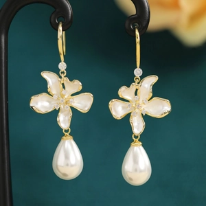 Macro shot of gold floral earrings with crystal accents and teardrop pearls