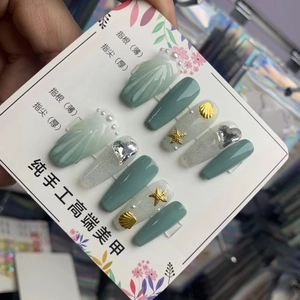 Détails de faux ongles faits main avec textures de coquillages et charms d'étoiles