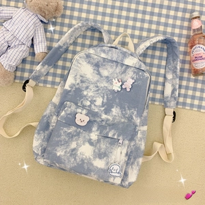 Detail of blue and white tie-dye canvas backpack with cute animal pins and plush bear décor