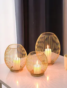 Close-up of three golden iron wire lanterns with white pillar candles on marble