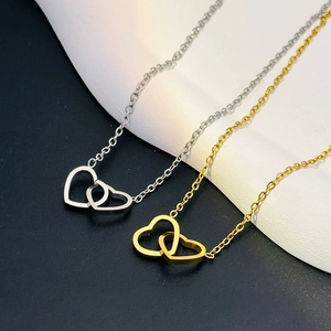 Macro detail of interlocking double heart pendant necklace in gold and silver finish