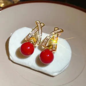 Gold plated crisscross stud earrings with baguette zircons and a red pearl pendant