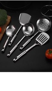 Macro shot of 5-piece stainless steel cooking utensils on black background with vegetables