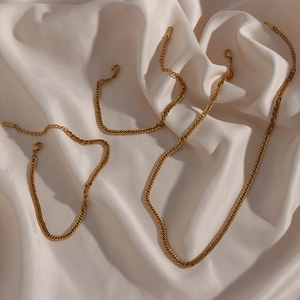 Close-up of three gold-plated Cuban link chains and bracelets on white silk fabric