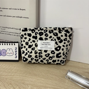 Detail of leopard print corduroy makeup bag with metal zipper on a wooden desk