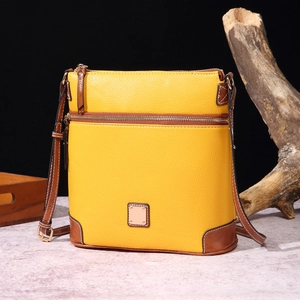 Detail showing pebbled yellow leather texture with brown contrast stitching on the crossbody bag