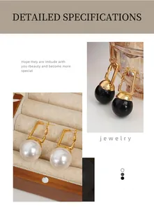 Détail de boucles d'oreilles dorées géométriques avec grandes perles noires et blanches