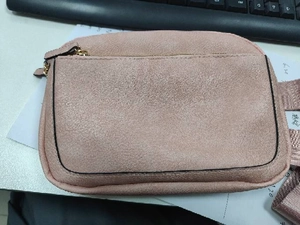 Detailed view of pink faux suede waist bag with golden zipper and adjustable strap