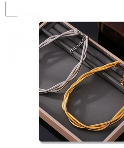 Close-up of gold and silver layered snake bone necklaces on a grey display tray