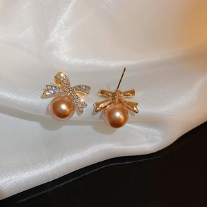 Détail des boucles d'oreilles nœud avec cristaux et perles sur fond de soie blanche