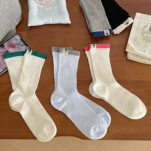 Japanese style colorful ribbed mid-calf socks with cute patches on a wooden background
