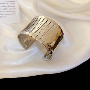 Detailed view of silver irregular wide open cuff bracelet on elegant white silk fabric