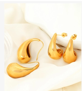Detailed macro shot of 18K gold plated teardrop earrings on white silk fabric