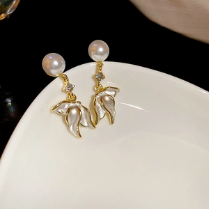 Détail de boucles d'oreilles perles avec pétales blancs et bords dorés sur porcelaine