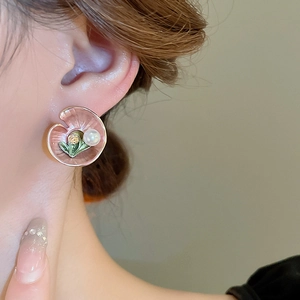Detail of vintage lotus leaf stud earring with pink enamel and faux pearl on ear