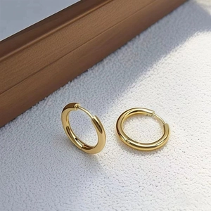 Close-up of polished gold-tone hoop earrings with a mirror-finish on a white background