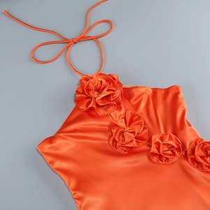 Detail of orange satin halter top featuring a 3D handmade fabric flower decoration