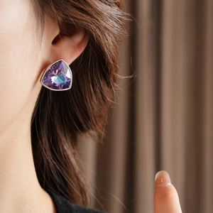 Vue macro d'une boucle d'oreille triangle avec cristal dégradé violet sur l'oreille d'un mannequin
