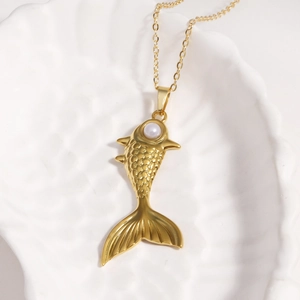 Vue détaillée du pendentif poisson rouge avec perle sur une chaîne dorée dans un coquillage