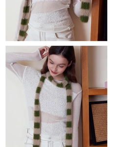 Detailansicht eines flauschigen beige-grün karierten Strickschals an einem Modell