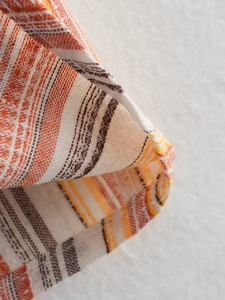 Detailed close-up of striped fabric texture in orange, brown and white knitted pattern