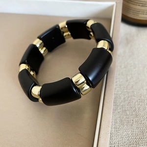 Detail view of acrylic retro bracelet with black matte beads and gold metal accents