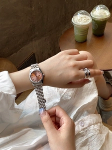 Close-up of a women's silver watch with pink dial and calendar on a lady's wrist