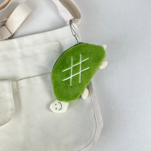 Close-up of plush turtle coin purse with green shell and white embroidery on canvas bag
