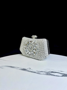 Elegant silver rhinestone evening clutch bag with crystal flower detail on marble surface