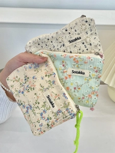 Floral embroidered small canvas cosmetic bag with zipper closure held in hand