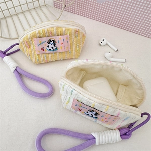 Detail of tweed shell-shaped headphone cases with cartoon dog patches and purple lanyards
