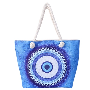 Detail of blue beach tote bag with evil eye pattern and white cotton rope handles