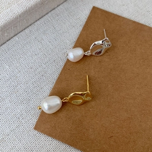 Detailed macro shot of irregular baroque pearl earrings with gold and silver metal accents
