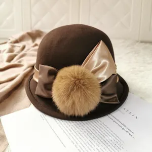Close-up of wool bowler hat with double satin bow and fluffy fur pompom detail