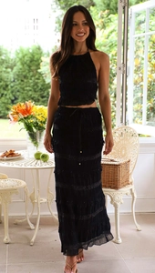 Detail of black two-piece vacation set featuring a halter pleated top and tiered skirt