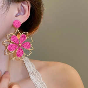 Nahaufnahme der Bast-Blumenohrringe in Pink mit Goldrahmen für den Strandurlaub