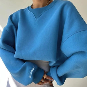 Close-up of bright blue crewneck sweatshirt featuring white INSTUNNING print on sleeve