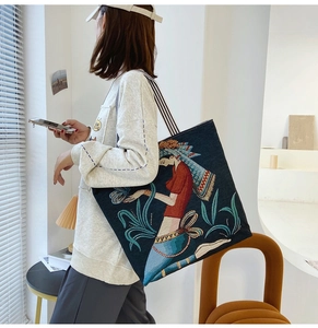 Artistic navy tote bag featuring ethnic embroidery and striped canvas shoulder straps