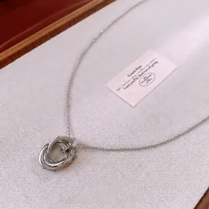 Minimalist silver interlocking triple-ring pendant necklace on a textured fabric background