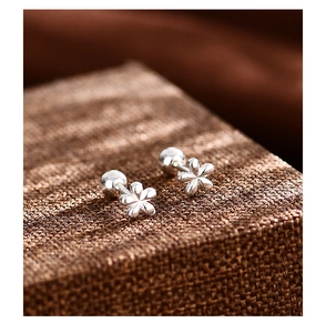 Vista macro de pendientes de flores de plata S999 con cierre de rosca sobre tejido
