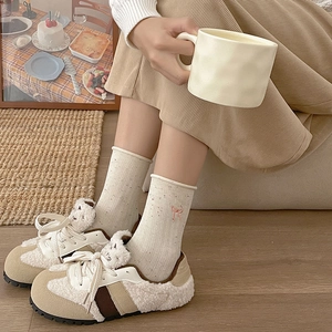 Detail of cream and brown faux shearling sneakers with vintage suede texture on floor
