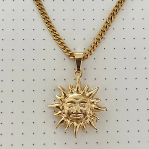 Macro detail of golden sun pendant necklace with anthropomorphic face and rays