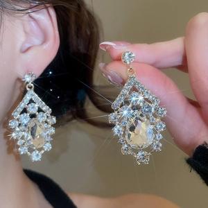 Detailed view of diamond-studded drop earrings with sparkling crystals and gold finish