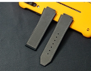 Detailed view of grey leather watch strap with rubber lining and white stitching