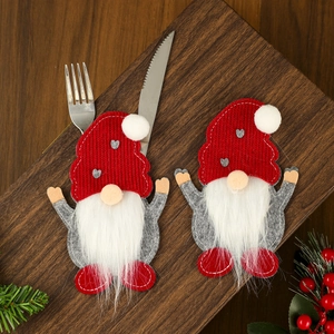Close-up of red and grey gnome silverware holders with knives and forks on wood