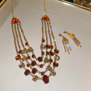 Close-up of vintage gold tassel necklace and earrings set with amber stones